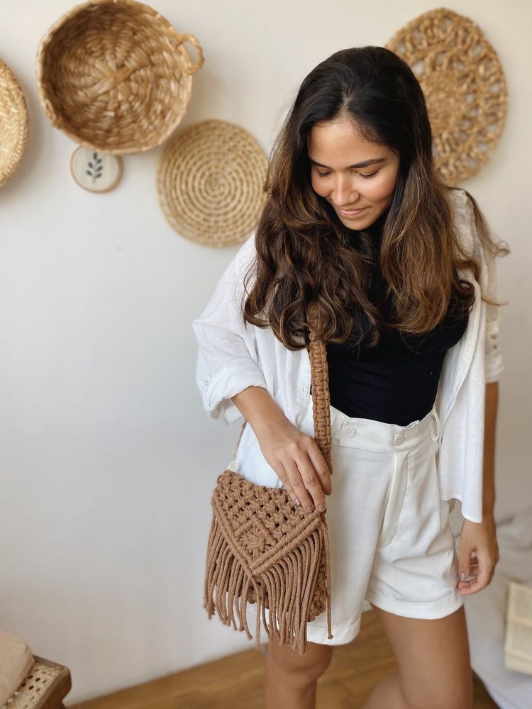 Mulher de pele clara usando blusa preta, quimono branco, shorta branco e bolsa transversal de macramê marrom