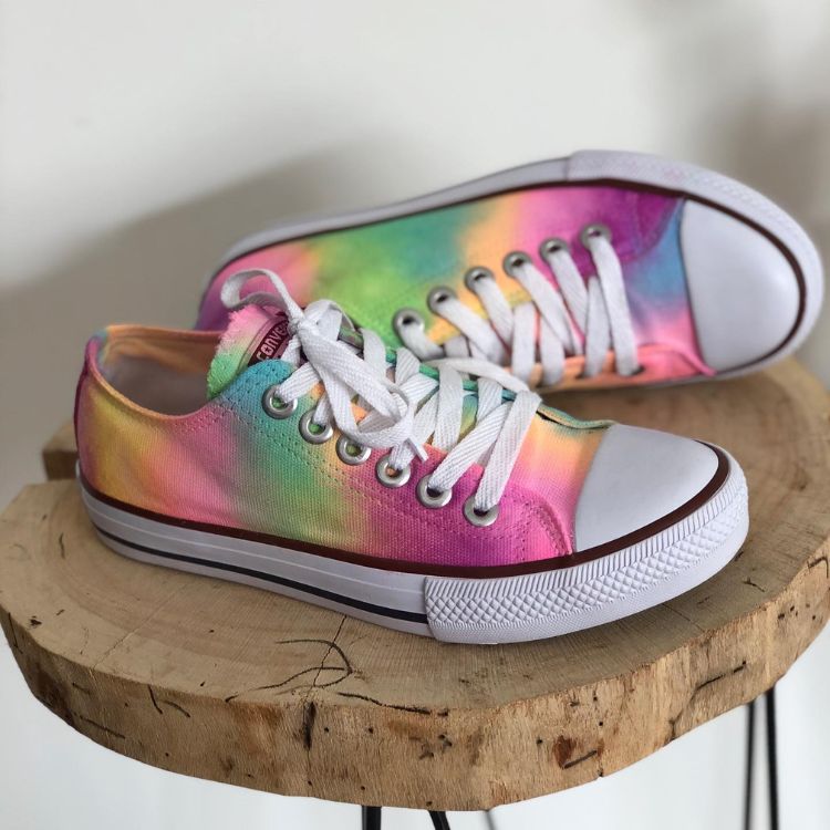 Par de tênis Converse baixo tie dye sobre mesinha redonda de madeira