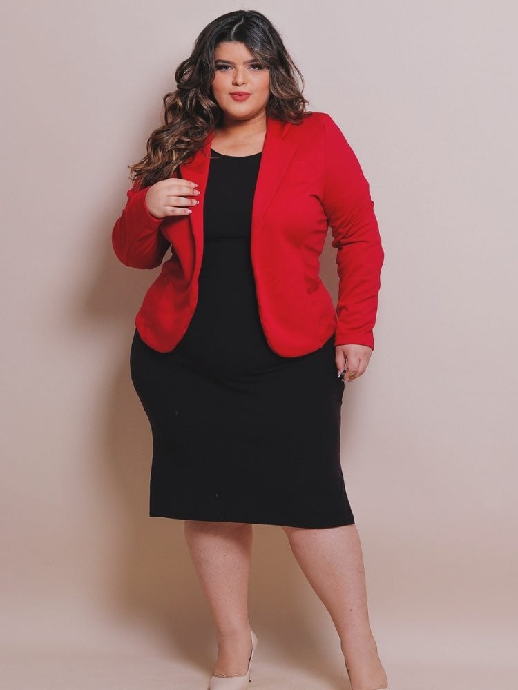 Mulher de pele clara usando vestido midi preto e blazer vermelho 