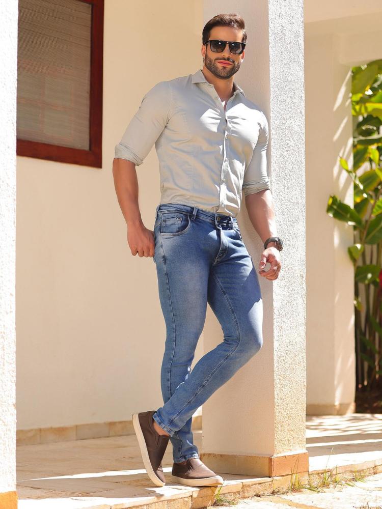 Homem de pele clara usando camisa social clara e calça jeans clara