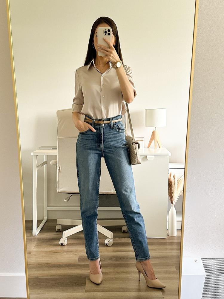 Mulher de pele clara usando camisa bege, calça jeans clara e salto alto 