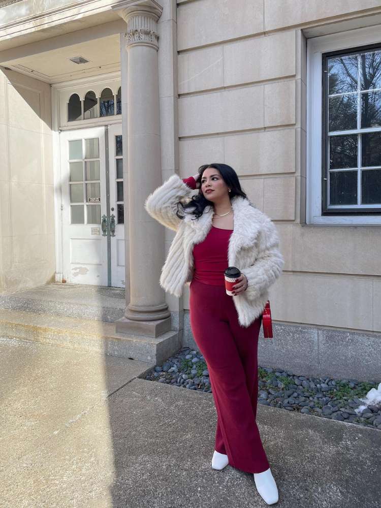 Mulher de pele clara usando blusa vermelha, calça vermelha e casaco branco de pele