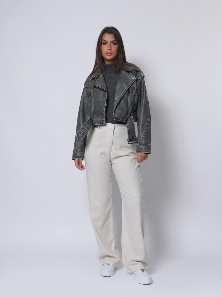 Mulher de pele clara usando blusa quente sob jaqueta biker cinza, wide leg branca e tênis