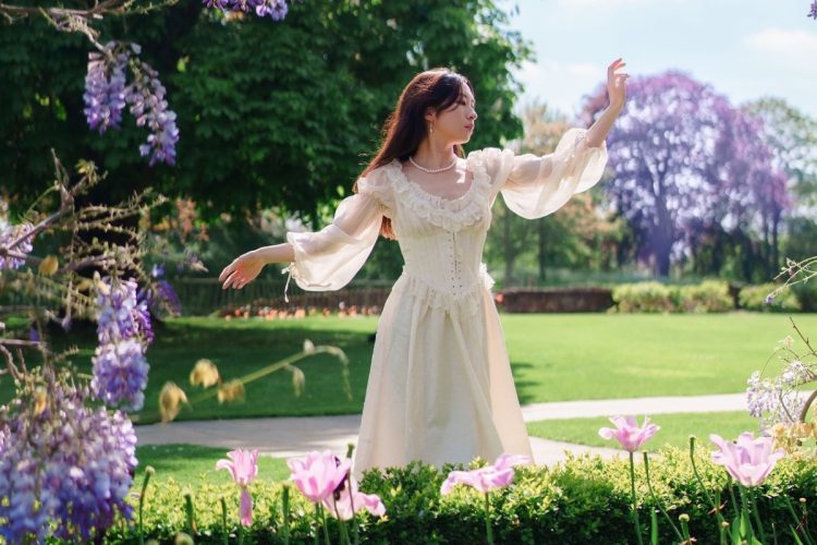 Mulher de origem asiática com vestido claro de babados e renda em jardim