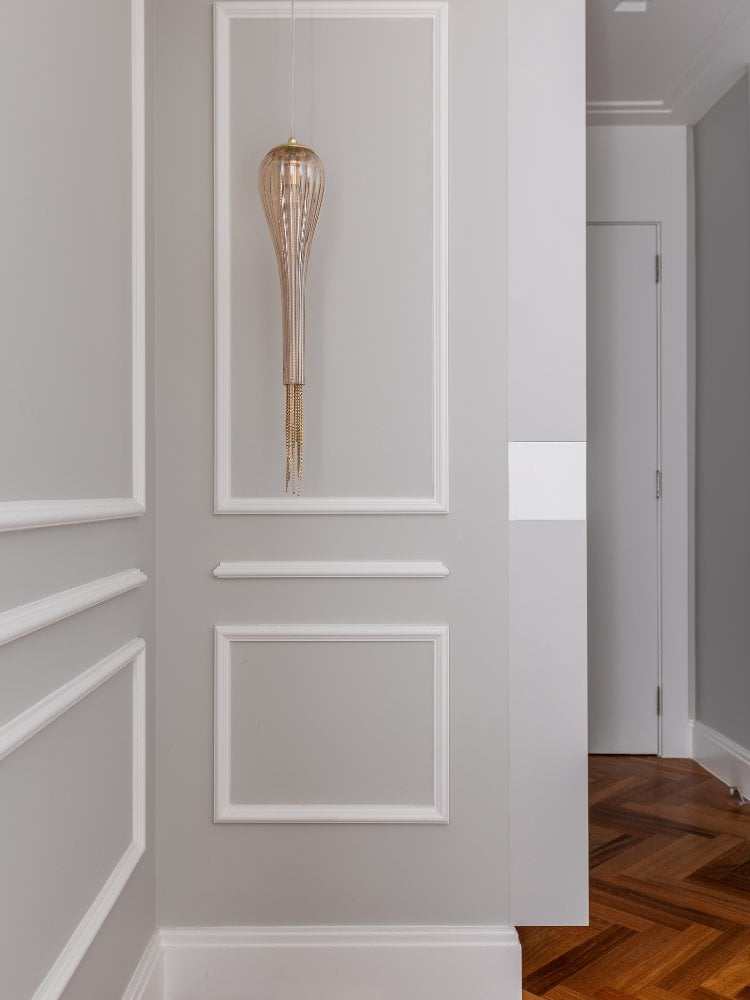 Paredes cinzas com boiserie branco e lustre dourado