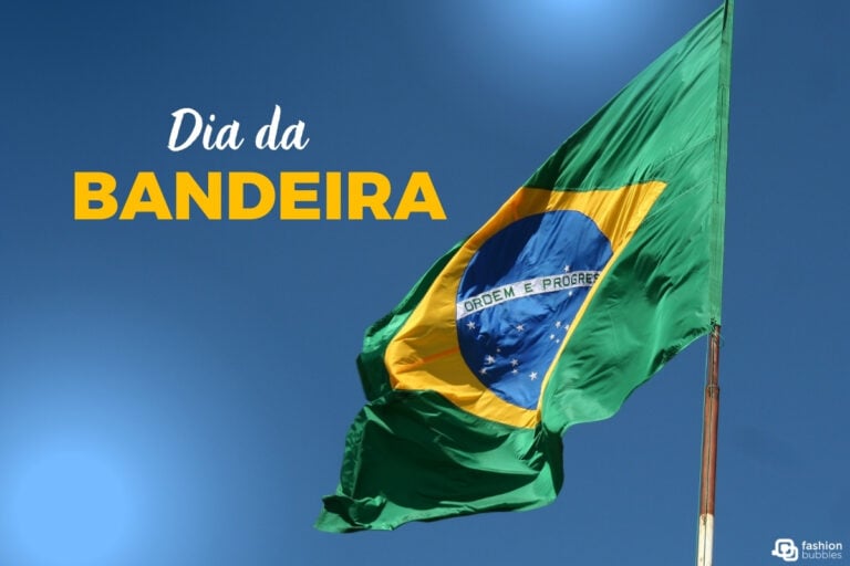 A imagem mostra a bandeira do Brasil tremulando ao vento, destacando suas cores verde, amarelo, azul e branco. No centro, o lema "Ordem e Progresso" é visível. O fundo é um céu azul claro. À esquerda, está escrito "Dia da Bandeira" em letras brancas e amarelas.