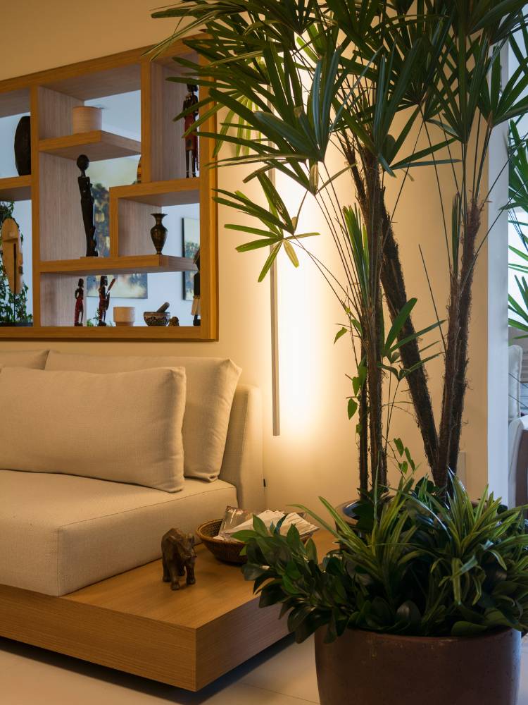 Foto de cantinho ao lado de sofá com parede vazada, planta, iluminação na parede e mesinha de madeira