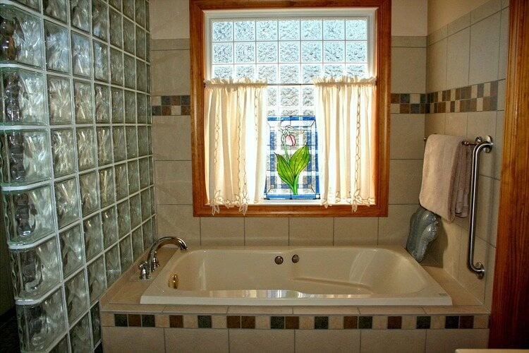 banheiro com banheira e janela com luz do sol batendo