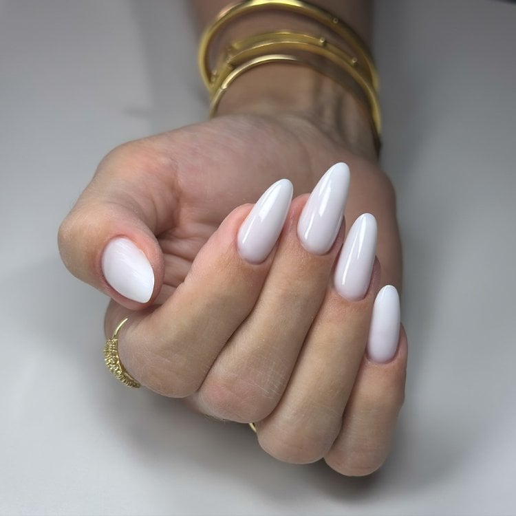 Mulher de pele clara usando esmalte branco em unhas almond