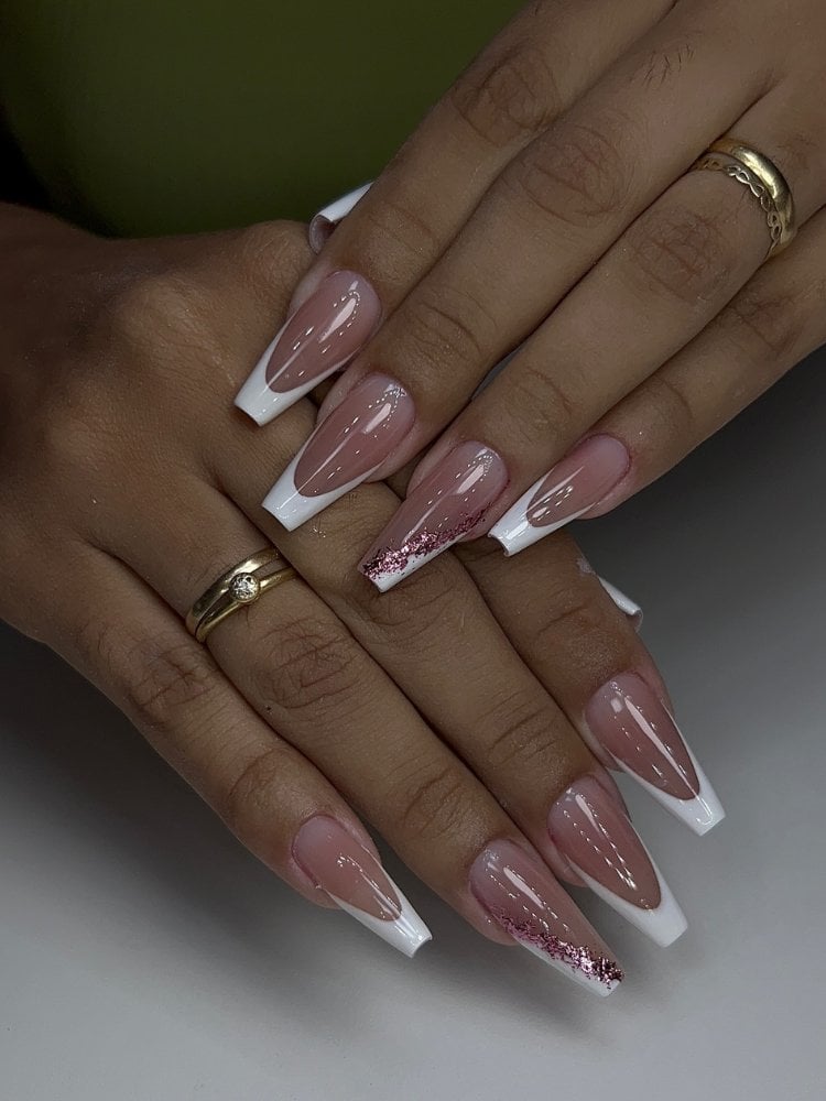 Mulher de pele morena usando unhas bailarina grandes, com base rosa antigo, francesinha e glitter rosa