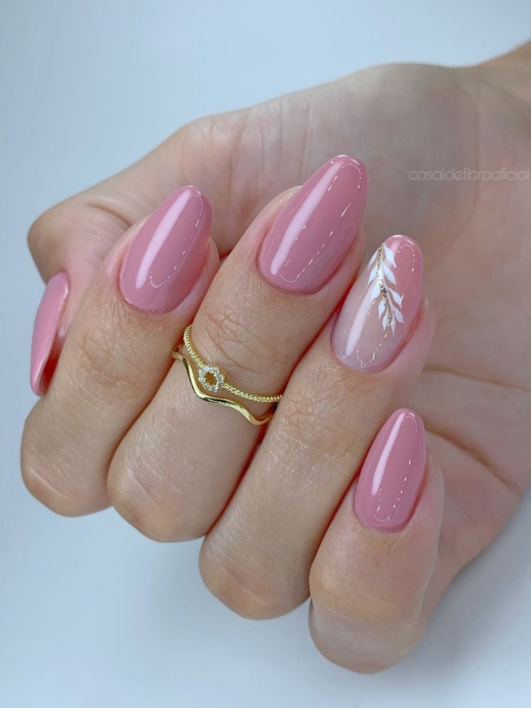 Mulher de pele clara usando esmalte rosa bem clarinho, com unha do anelar decorada com detalhe branco de ramo