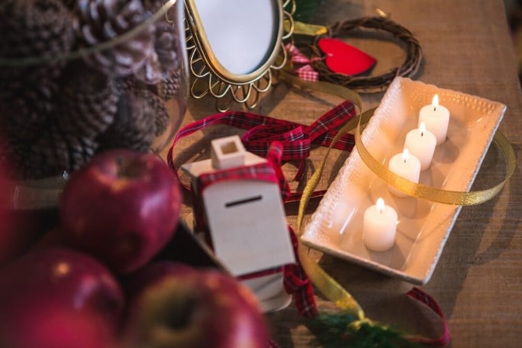 Foto de mesa de madeira com maçãs, velas, espelho, fitas e corações de papel