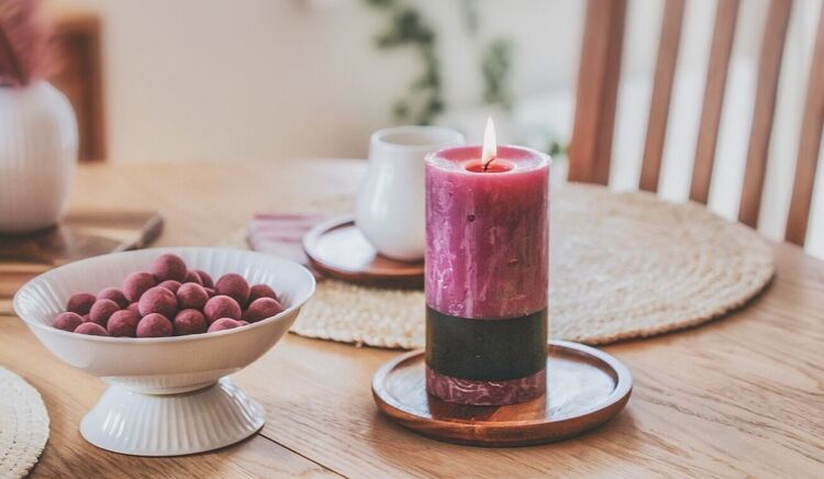 mesa de jantar com travessa de uvas e uma vela de sete dias vermelha acesa