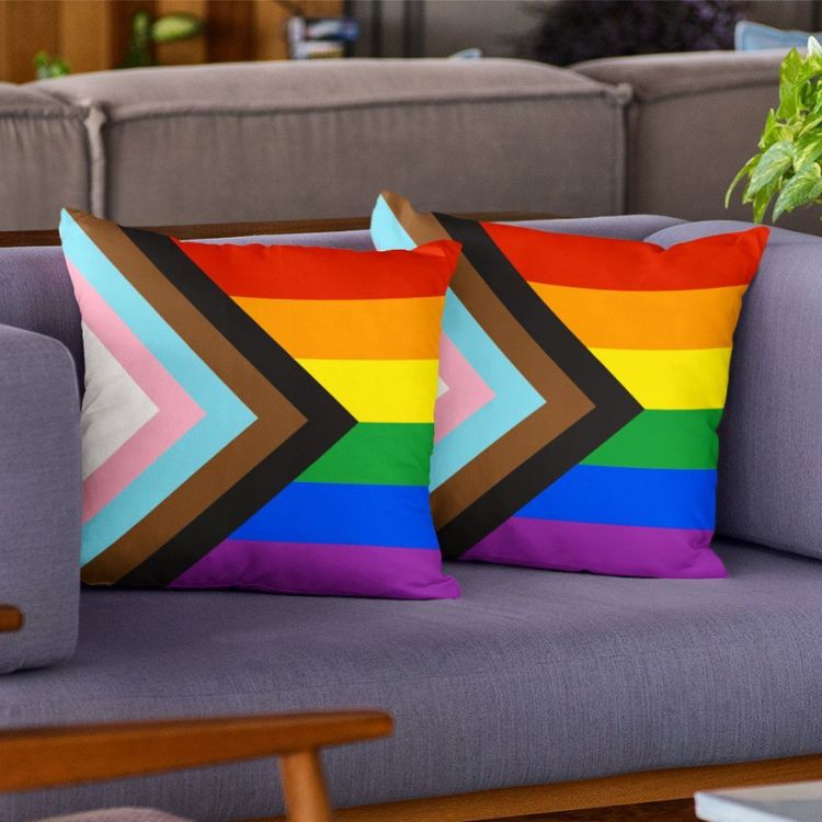 Sofá cinza com duas almofadas com estampa da bandeira LGBTQIAPN+