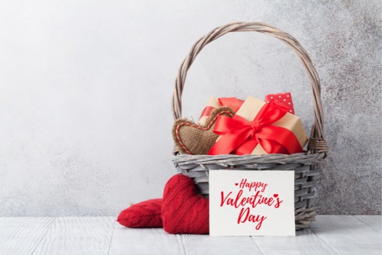 Foto de fundo cinza com cesta do Dia dos Namorados, com presentes, corações e cartão de Happy Valentine's Day