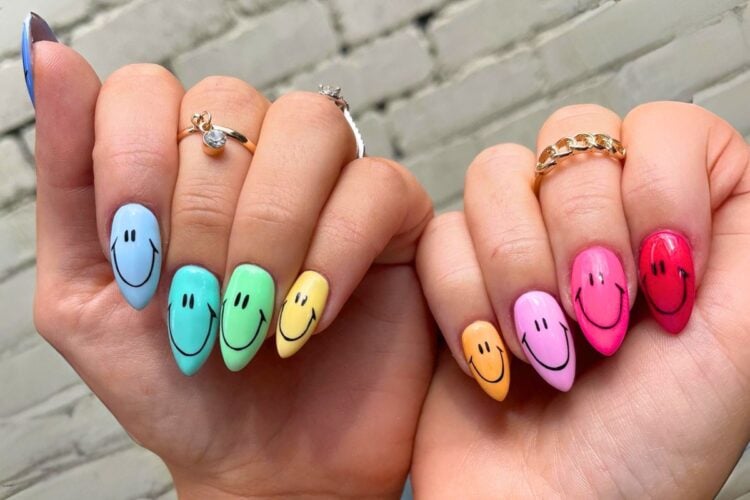 Mãos com unhas coloridas com carinha feliz