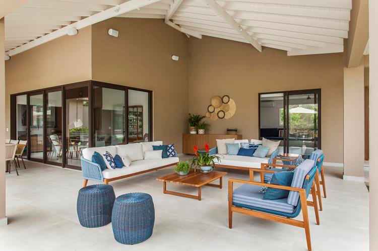 ambiente externo de casa com poltronas e sofás nas cores branca e azul