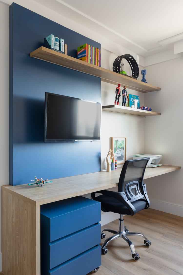 quarto com mesa de madeira, painel azul e cadeira preta