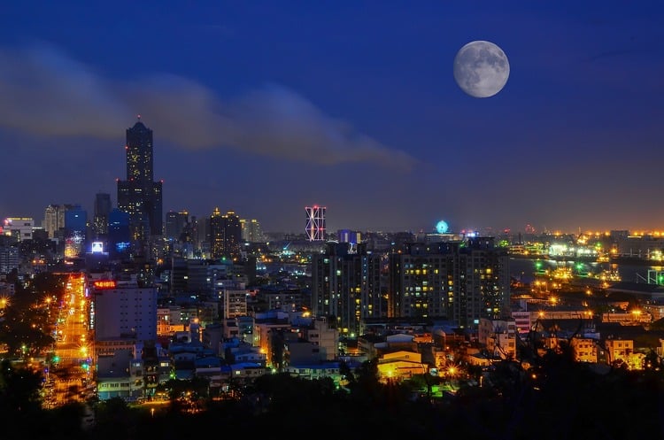 imagem de uma cidade grande, com muitos prédios e uma lua cheia