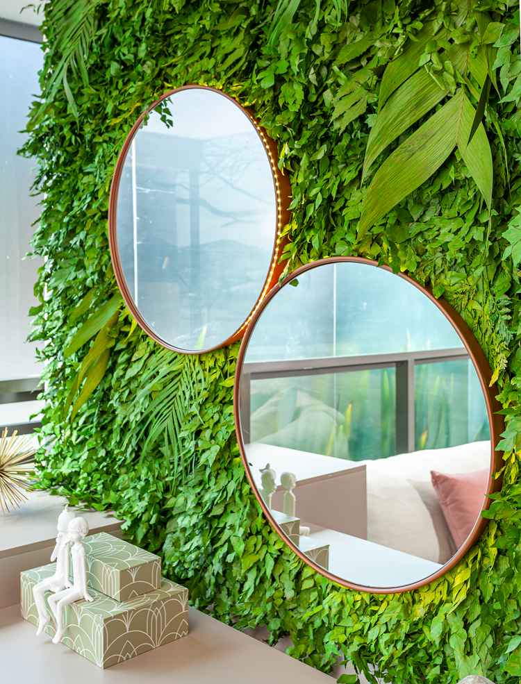 foto de dois espelhos redondos apoiados em parede de folhas