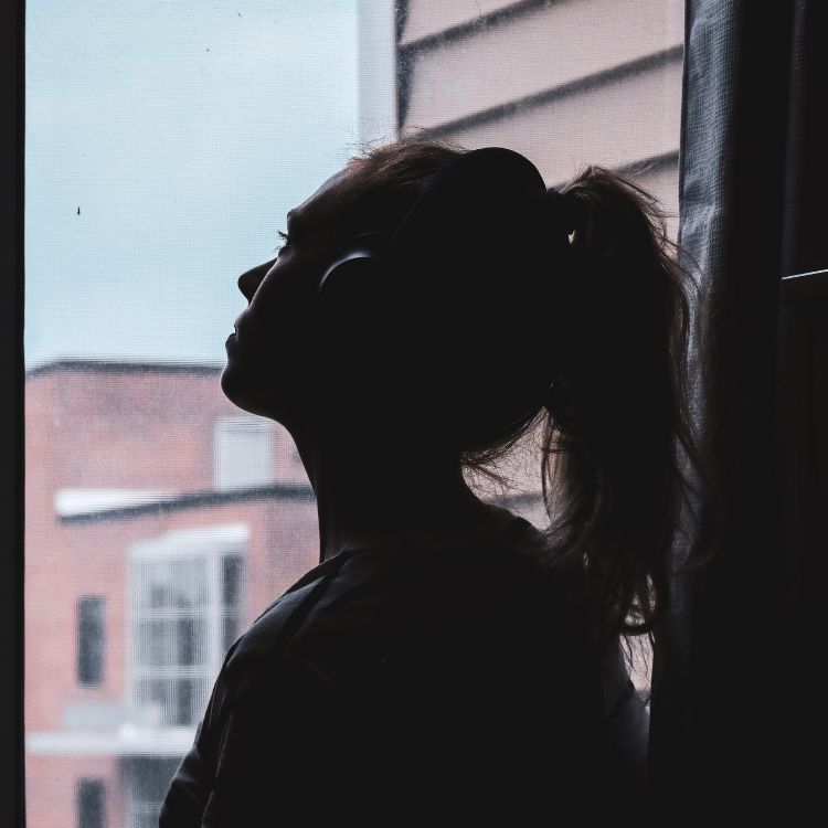 mulher em foto escura olhando para janela