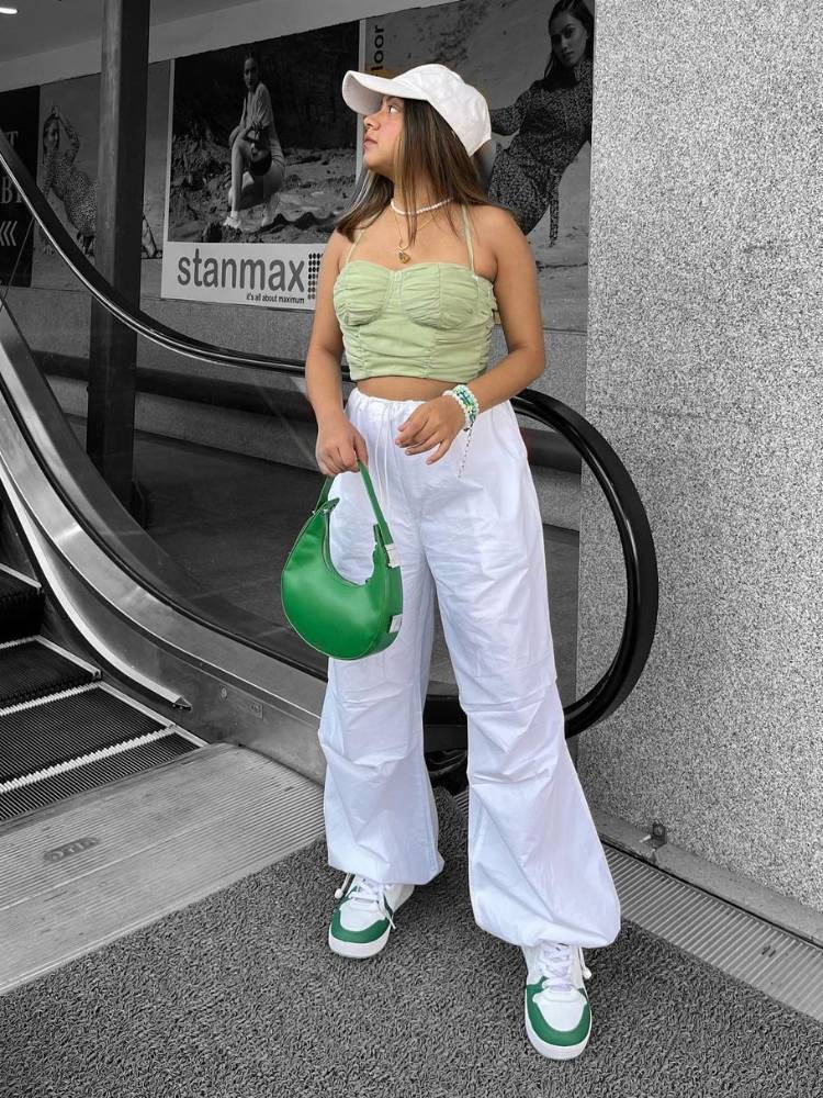 mulher usando top verde e calça parachute branca