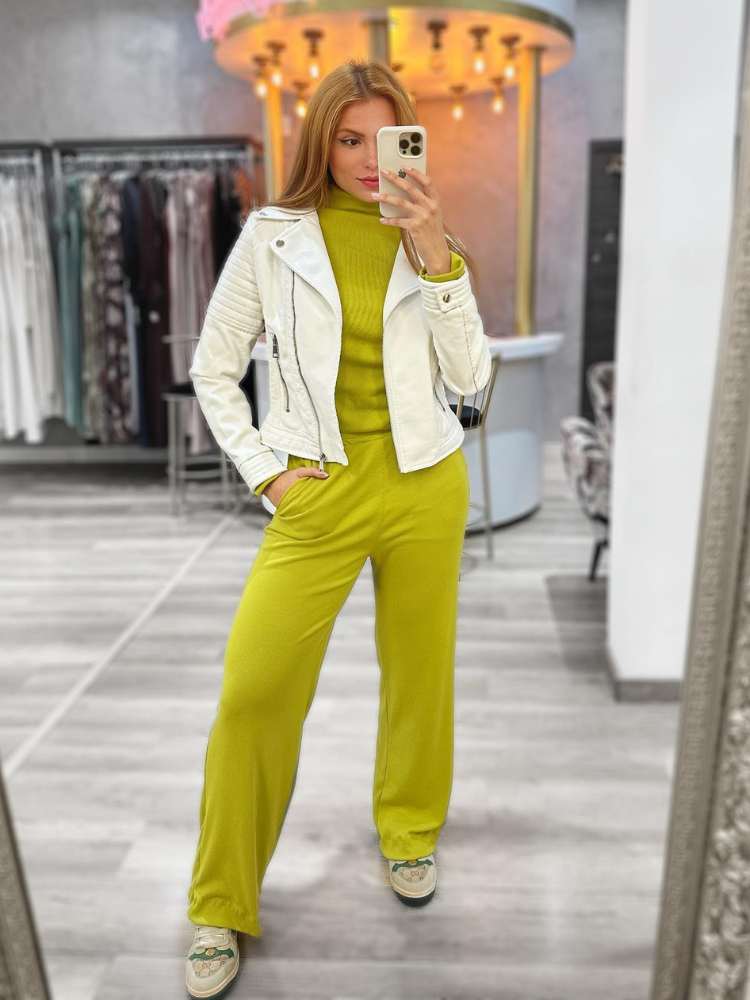 Looks com couro: mulher usando macacão verde abacate, jaqueta branca de couro + tênis