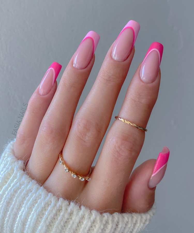 A imagem retrata um mão com unhas decoradas de rosa. Os esmaltes usados são de cor: pink, rosa claro e nude. O esmalte está uniforme e brilhante. As unhas estão no formato quadrado.