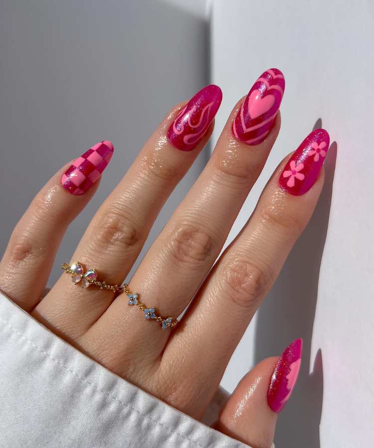 A imagem retrata um par de mãos com unhas pintadas de rosa. Os esmaltes usados são de cor: pink e rosa claro. O esmalte está uniforme e brilhante. As unhas estão no formato oval.