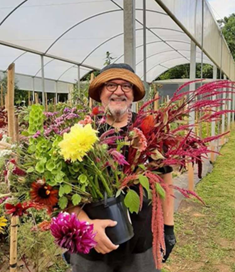 Ator Luis Melo segurando vaso de flores em floricultura