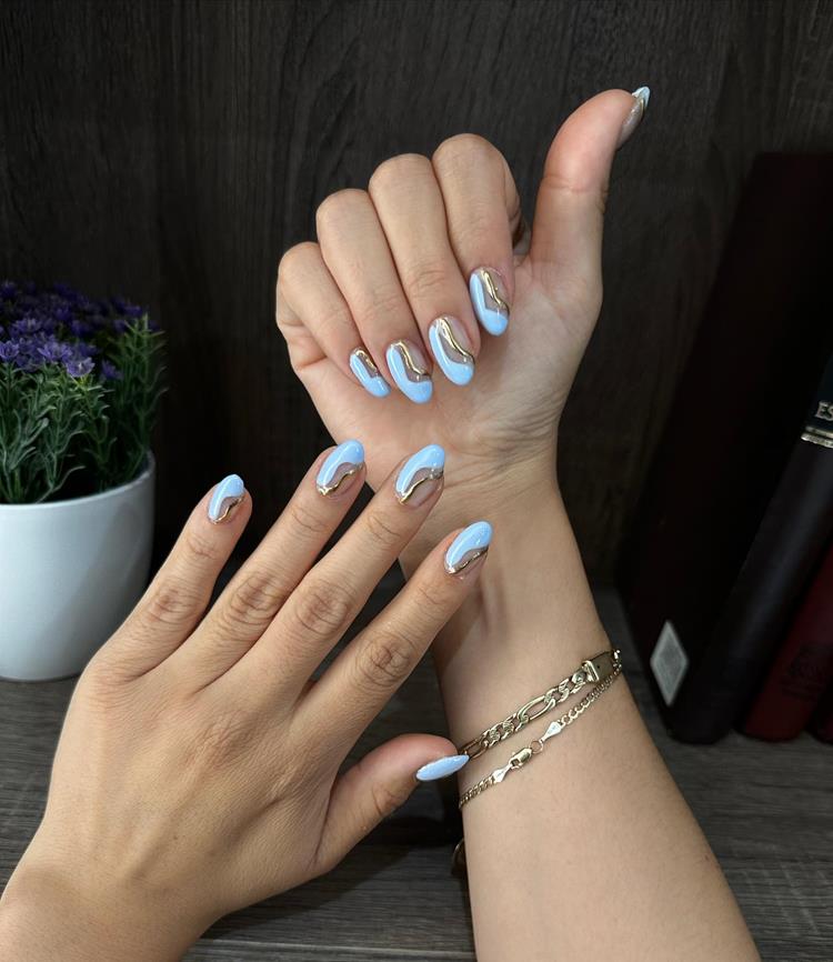 mãos com  blueberry milk nails e nail art dourada