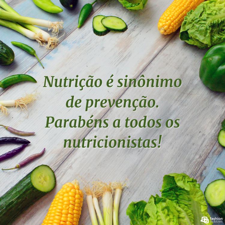 Foto de mesa de madeira com legumes e verdura ao redor e frase "Nutrição é sinônimo de prevenção. Parabéns a todos os nutricionistas!" no meio 