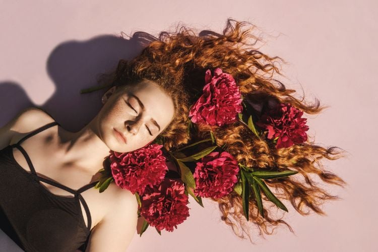 mulher ruiva deitada com flores pink nos cabelos