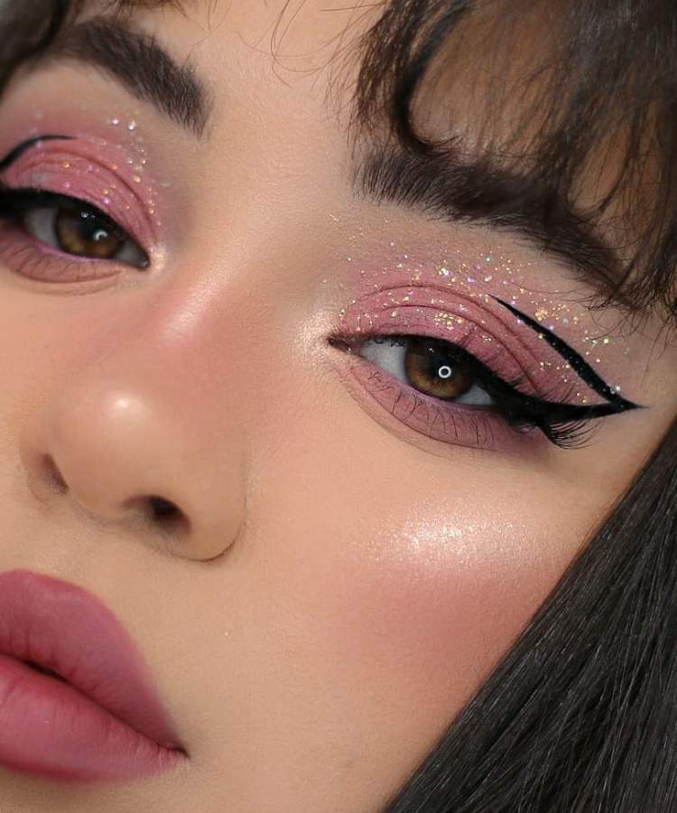 Mulher maquiada com trends de make 2023: olho com glitter, delineado, pele matte