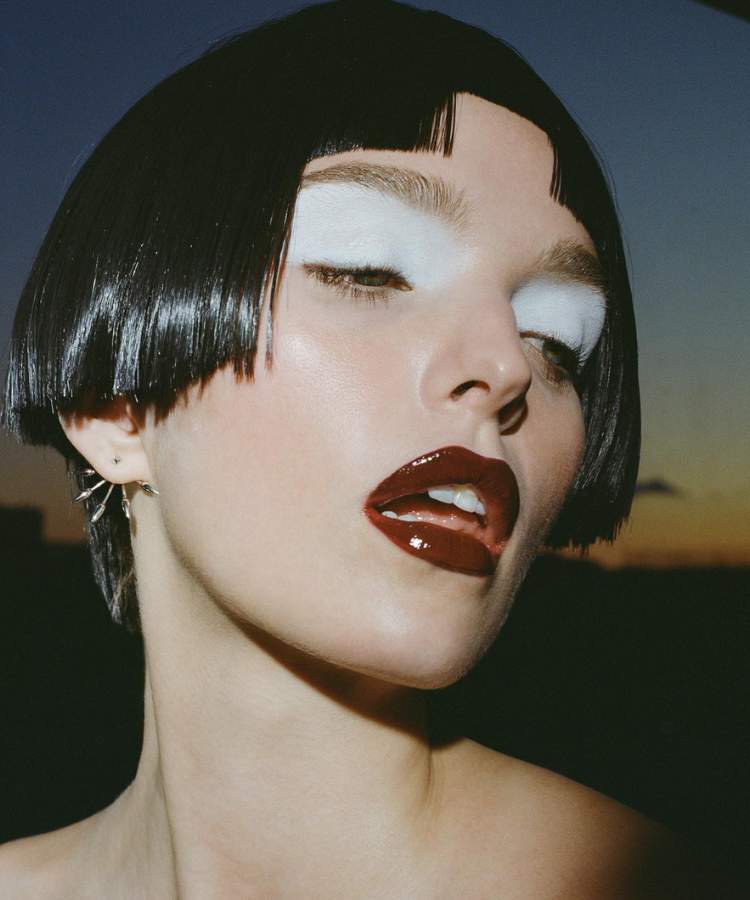 Mulher maquiada com tendências de maquiagem para 2023: sombra branca esfumada, lábios de vinil, pele clean