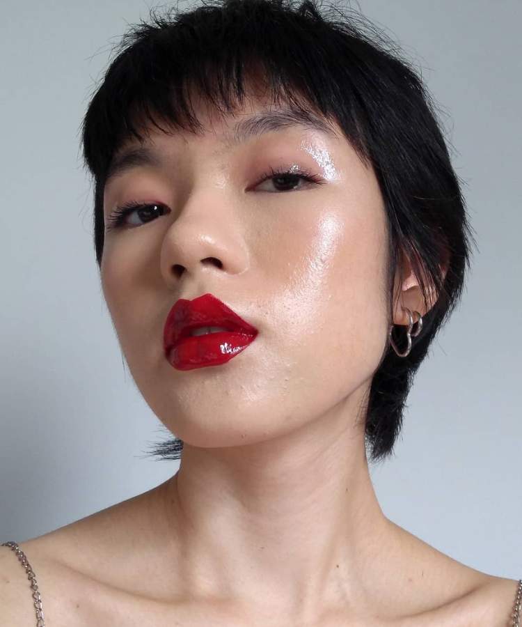 Mulher maquiada com trends de make 2023: lábios de vinil, pele clean