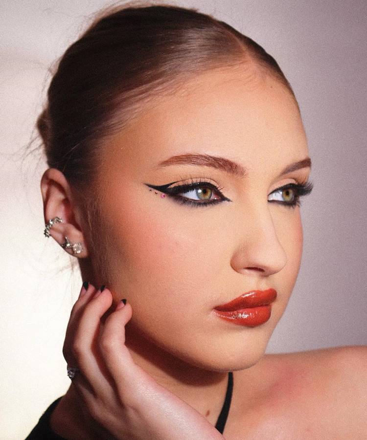 Mulher maquiada com tendências de maquiagem para 2023: foxy eyes, euphoria, lábios de gloss