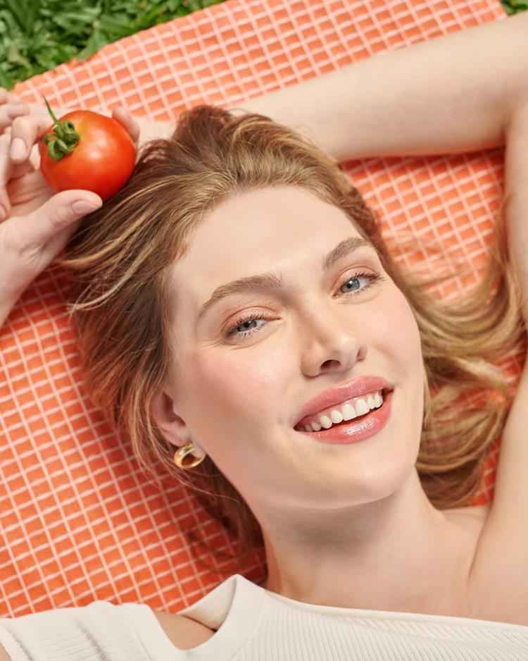 mulher deitada mostrando maquiagem tomato girl