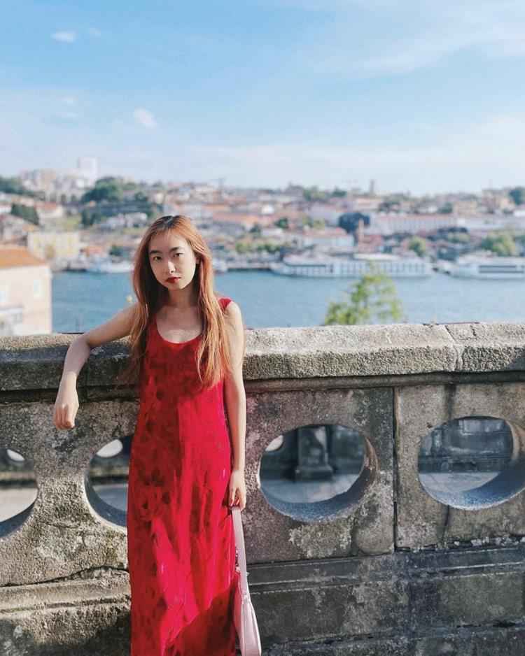 mulher com vestido longo vermelho em paisagem ao ar livro, rio ao fundo da tomato girl