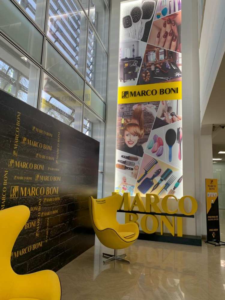 Entrada da empresa Marco Boni, poltronas amarelas, nome da marca bem grande e painel com fotos de produtos