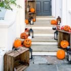 Foto de porta da frente e degraus decorados com abóboras, aranhas e velas para o Dia das Bruxas