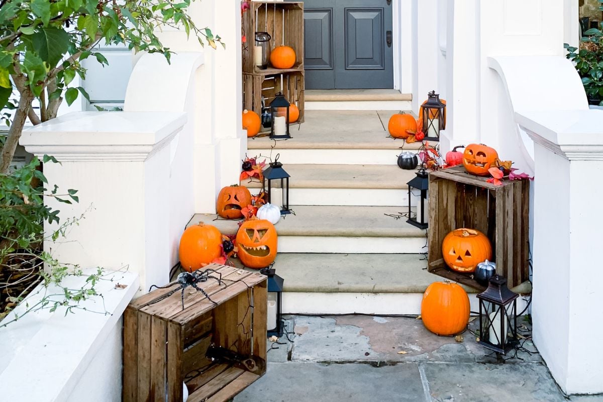 Foto de porta da frente e degraus decorados com abóboras, aranhas e velas para o Dia das Bruxas