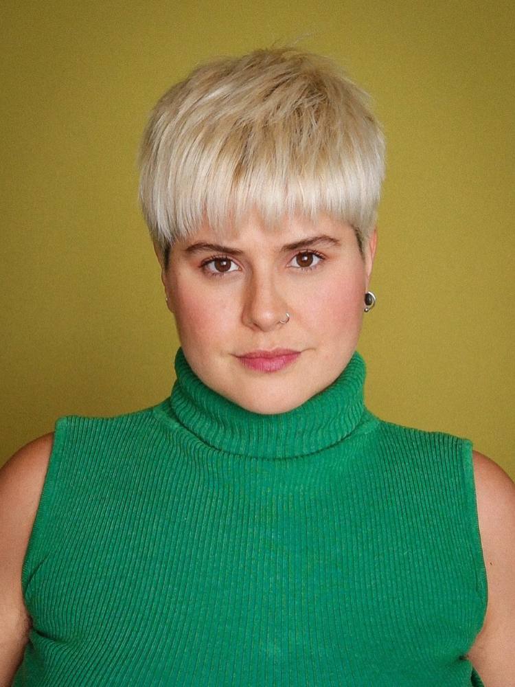 Mulher d epele clara usando blusa verde de gola alta e cabelo bowl cut repicado platinado