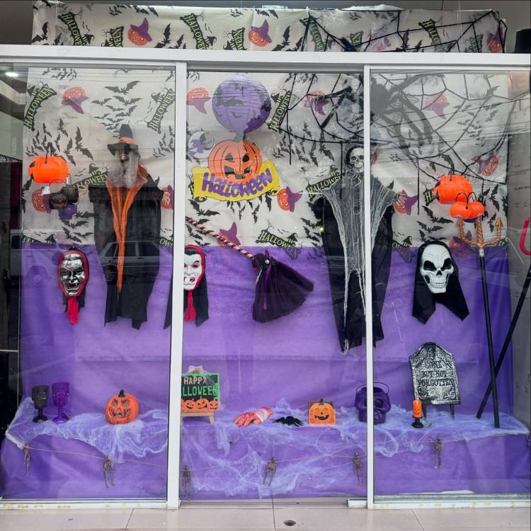 Vitrine de Halloween com pano roxo, máscaras de personagens de filmes de terror, abóboras e teias 