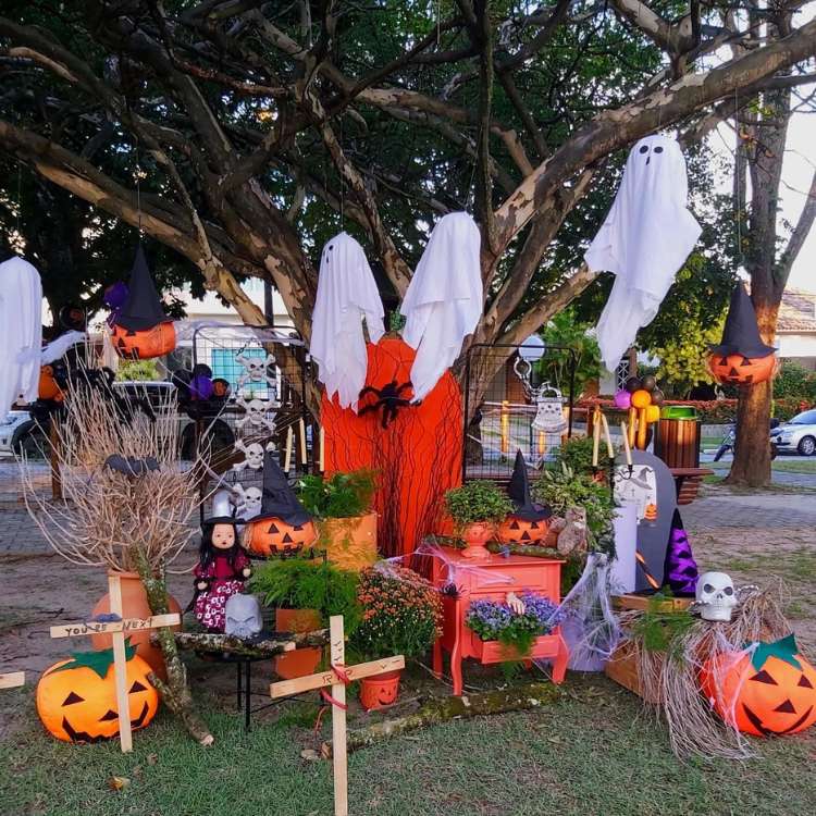 Quintal decorado para o Halloween, com fantasmas pendurados, abóboras, bruxas e mais 