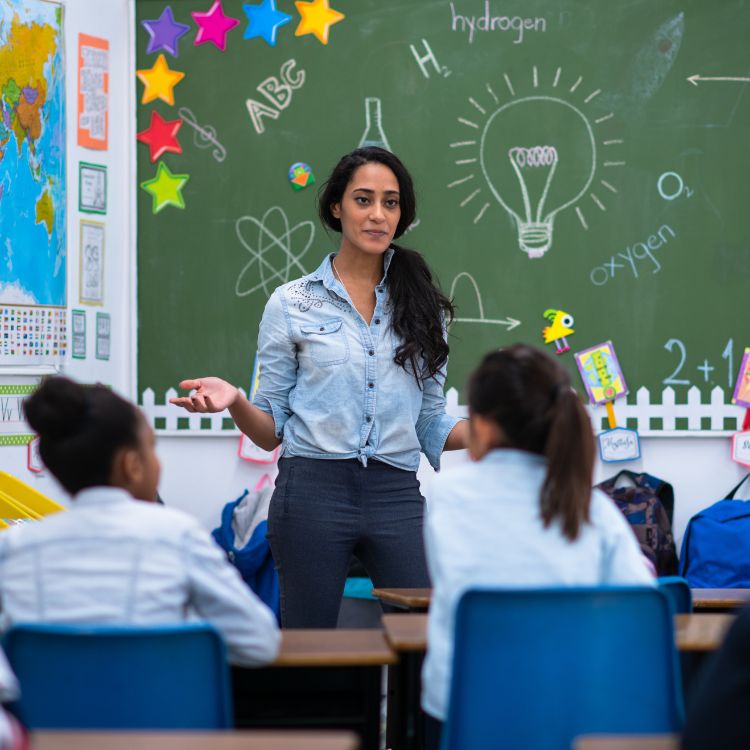 Mulher de pele morena dando aula para crianças 