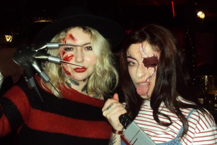 Foto de duas mulheres de pele clara, uma fantasiada com make de Freddy Krueger e outra fantasiada com make de Chucky