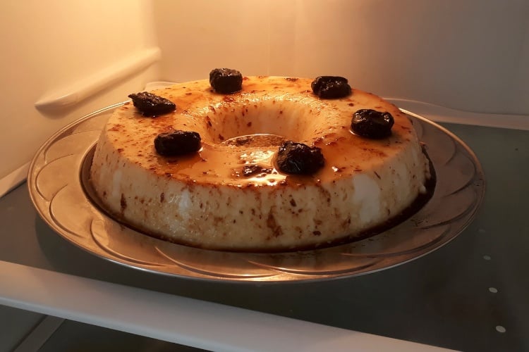 Foto de manjar de coco com calda de ameixa em prateleira na geladeira 