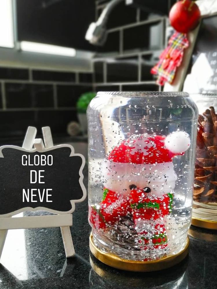 Foto de "globo de neve" feito em casa, sobre mesa e ao lado de mini lousa escrito "globo de neve"