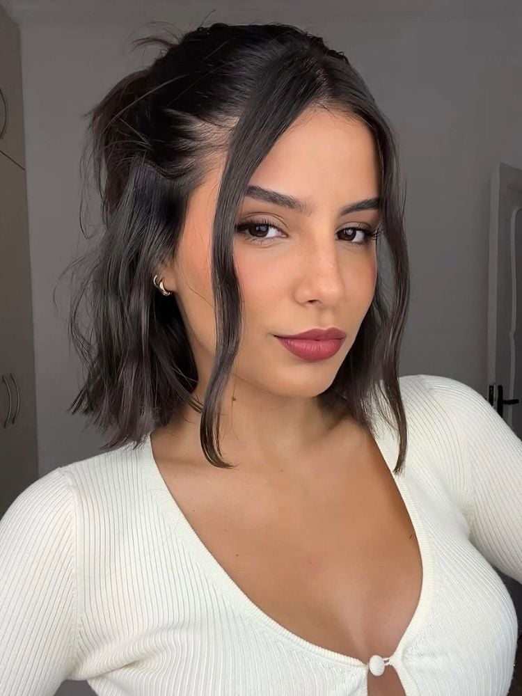 Mulher de pele clara com blusa branca e cabelo curto moreno preso com franja 